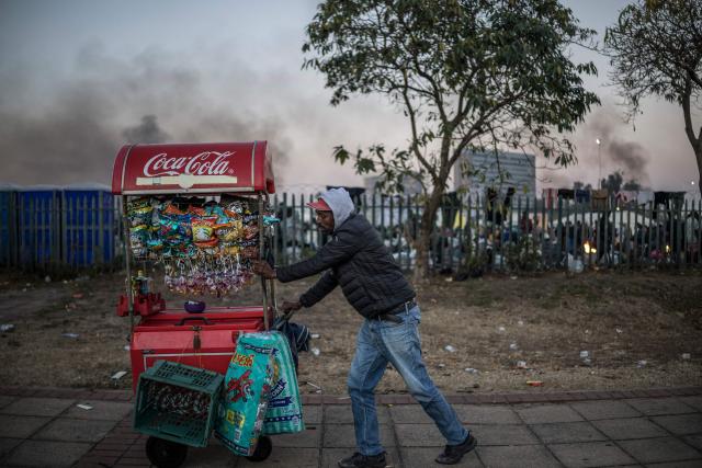 A street vendor pushes his cart as he sells food to undocumented migrants gathering outside the gate of the Durban Drive In in Durban, on June 27, 2026 where they will be registered by South African Immigration Officers ahead of their repatriation. Thousands of Malawians were awaiting clearance in makeshift encampments in South Africa Friday as tension mounted before an unofficial June 30 ultimatum for undocumented migrants to leave the country.
Citizen-led groups have rallied behind the unauthorised Tuesday deadline after weeks of protests, attacks on businesses and threats against illegal migrants in which two Mozambican nationals and a Malawian have been killed. (Photo by MARCO LONGARI / AFP)