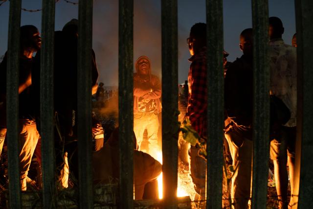 Undocumented migrants warm up by a camp fire at the Durban Drive In in Durban, on June 27, 2026 where they will be registered by South African Immigration Officers ahead of their repatriation. Thousands of Malawians were awaiting clearance in makeshift encampments in South Africa Friday as tension mounted before an unofficial June 30 ultimatum for undocumented migrants to leave the country.
Citizen-led groups have rallied behind the unauthorised Tuesday deadline after weeks of protests, attacks on businesses and threats against illegal migrants in which two Mozambican nationals and a Malawian have been killed. (Photo by MARCO LONGARI / AFP)