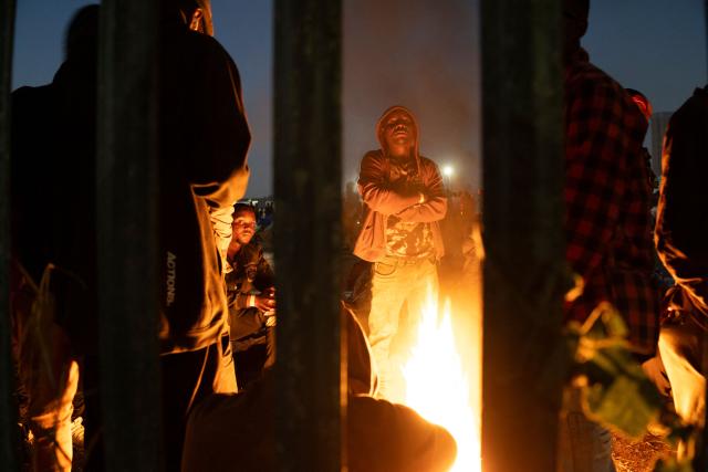 Undocumented migrants warm up by a camp fire at the Durban Drive In in Durban, on June 27, 2026 where they will be registered by South African Immigration Officers ahead of their repatriation. Thousands of Malawians were awaiting clearance in makeshift encampments in South Africa Friday as tension mounted before an unofficial June 30 ultimatum for undocumented migrants to leave the country.
Citizen-led groups have rallied behind the unauthorised Tuesday deadline after weeks of protests, attacks on businesses and threats against illegal migrants in which two Mozambican nationals and a Malawian have been killed. (Photo by MARCO LONGARI / AFP)