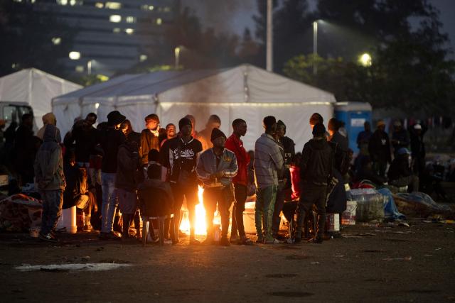 Undocumented migrants warm up by a camp fire at the Durban Drive In in Durban, on June 27, 2026 where they will be registered by South African Immigration Officers ahead of their repatriation. Thousands of Malawians were awaiting clearance in makeshift encampments in South Africa Friday as tension mounted before an unofficial June 30 ultimatum for undocumented migrants to leave the country.
Citizen-led groups have rallied behind the unauthorised Tuesday deadline after weeks of protests, attacks on businesses and threats against illegal migrants in which two Mozambican nationals and a Malawian have been killed. (Photo by MARCO LONGARI / AFP)