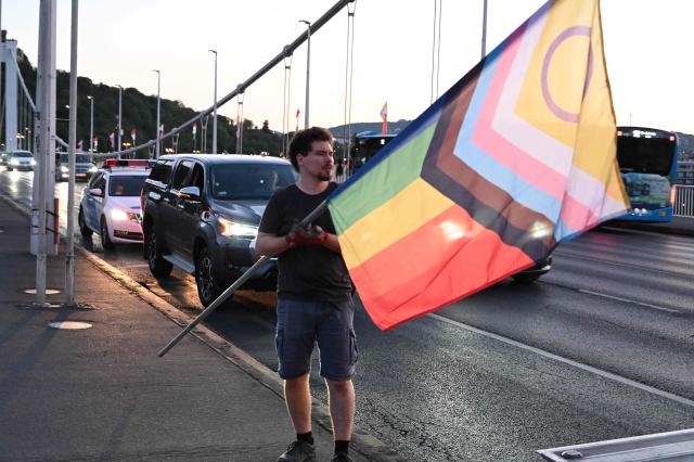 Local workers replace 'Progress Pride' rainbow flags on the Erzsebet Bridge in Budapest, Hungary, on June 26, 2026, a day before Budapest Pride. A right-wing sympathizer removed several flags and threw them into the Danube, after which activists from far-right parliamentary party, the 'Our Homeland Movement' placed Hungarian national flags on the bridge few days ago. (Photo by Attila KISBENEDEK / AFP)