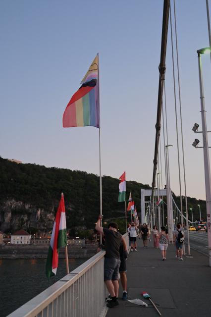 Local workers replace 'Progress Pride' rainbow flags on the Erzsebet Bridge in Budapest, Hungary, on June 26, 2026, a day before Budapest Pride. A right-wing sympathizer removed several flags and threw them into the Danube, after which activists from far-right parliamentary party, the 'Our Homeland Movement' placed Hungarian national flags on the bridge few days ago. (Photo by Attila KISBENEDEK / AFP)
