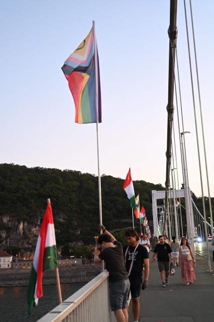 Local workers replace 'Progress Pride' rainbow flags on the Erzsebet Bridge in Budapest, Hungary, on June 26, 2026, a day before Budapest Pride. A right-wing sympathizer removed several flags and threw them into the Danube, after which activists from far-right parliamentary party, the 'Our Homeland Movement' placed Hungarian national flags on the bridge few days ago. (Photo by Attila KISBENEDEK / AFP)