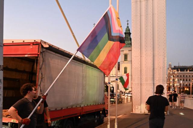 Local workers replace 'Progress Pride' rainbow flags on the Erzsebet Bridge in Budapest, Hungary, on June 26, 2026, a day before Budapest Pride. A right-wing sympathizer removed several flags and threw them into the Danube, after which activists from far-right parliamentary party, the 'Our Homeland Movement' placed Hungarian national flags on the bridge few days ago. (Photo by Attila KISBENEDEK / AFP)