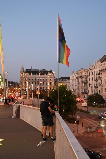 Local workers replace 'Progress Pride' rainbow flags on the Erzsebet Bridge in Budapest, Hungary, on June 26, 2026, a day before Budapest Pride. A right-wing sympathizer removed several flags and threw them into the Danube, after which activists from far-right parliamentary party, the 'Our Homeland Movement' placed Hungarian national flags on the bridge few days ago. (Photo by Attila KISBENEDEK / AFP)