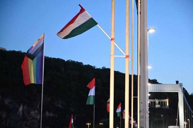 Local workers replace 'Progress Pride' rainbow flags on the Erzsebet Bridge in Budapest, Hungary, on June 26, 2026, a day before Budapest Pride. A right-wing sympathizer removed several flags and threw them into the Danube, after which activists from far-right parliamentary party, the 'Our Homeland Movement' placed Hungarian national flags on the bridge few days ago. (Photo by Attila KISBENEDEK / AFP)