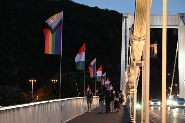 The 'Progress Pride' rainbow flags is seen on the Erzsebet Bridge in Budapest, Hungary, on June 26, 2026, a day before Budapest Pride. A right-wing sympathizer removed several flags and threw them into the Danube, after which activists from far-right parliamentary party, the 'Our Homeland Movement' placed Hungarian national flags on the bridge few days ago. (Photo by Attila KISBENEDEK / AFP)