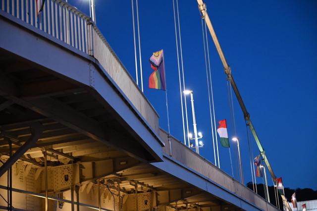 The 'Progress Pride' rainbow flags is seen on the Erzsebet Bridge in Budapest, Hungary, on June 26, 2026, a day before Budapest Pride. A right-wing sympathizer removed several flags and threw them into the Danube, after which activists from far-right parliamentary party, the 'Our Homeland Movement' placed Hungarian national flags on the bridge few days ago. (Photo by Attila KISBENEDEK / AFP)