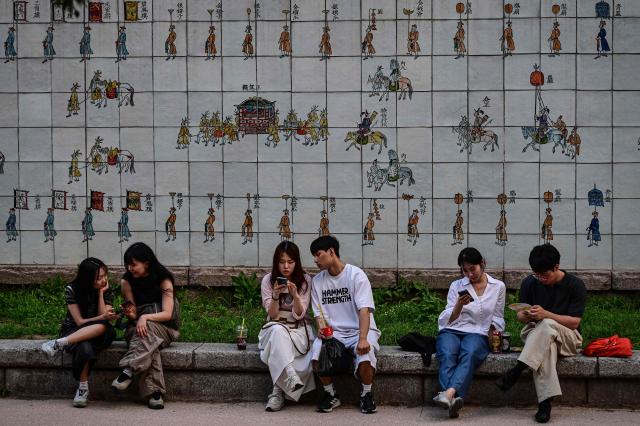 People relax near the Cheonggyecheon Stream in Seoul on June 27, 2026. (Photo by Jade GAO / AFP)