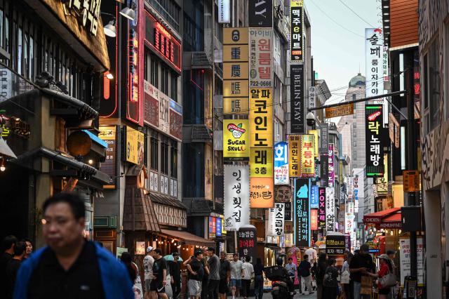 People walk through a food alley in Seoul on June 27, 2026. (Photo by Jade GAO / AFP)