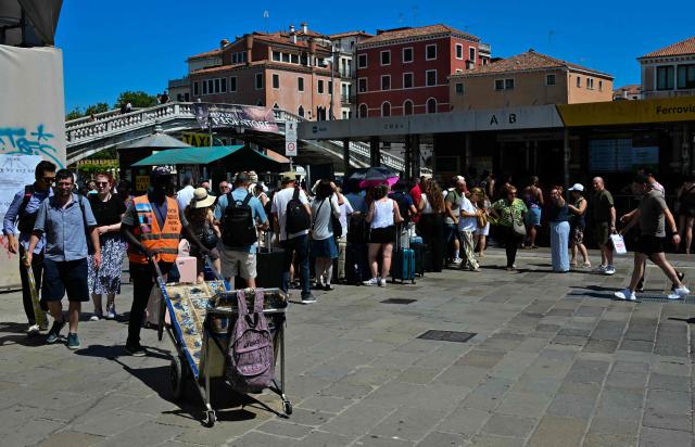 Tourists queue to board the "Vaporetto" waterbus to the city center during a heatwave in Venice on June 27, 2026. (Photo by Stefano RELLANDINI / AFP)
