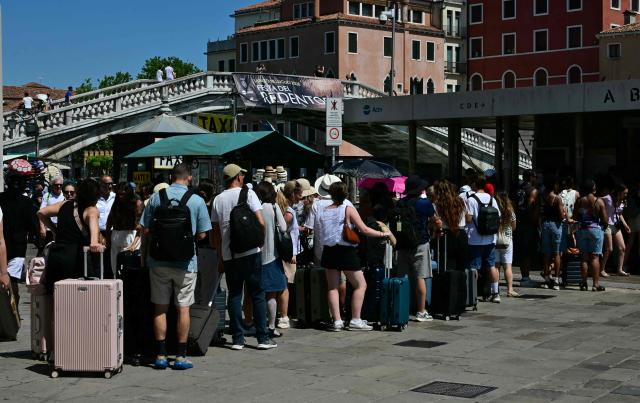 Tourists queue to board the "Vaporetto" waterbus to the city center during a heatwave in Venice on June 27, 2026. (Photo by Stefano RELLANDINI / AFP)