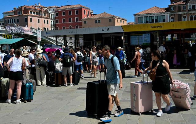 Tourists queue to board the "Vaporetto" waterbus to the city center during a heatwave in Venice on June 27, 2026. (Photo by Stefano RELLANDINI / AFP)