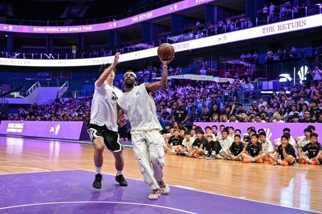 USA's basketball player Kyrie Irving (R) goes for the shot in an event with fans during his World Tour with the Chinese brand ANTA titled "The Return" in Chengdu, in China's southwestern Sichuan province on June 27, 2026. (Photo by Hector RETAMAL / AFP)
