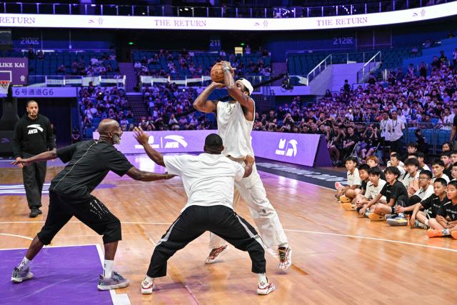 USA's basketball player Kyrie Irving (R) is guarded by his father Drederick Irving (L) in an event with fans during his World Tour with the Chinese brand ANTA titled "The Return" in Chengdu, in China's southwestern Sichuan province on June 27, 2026. (Photo by Hector RETAMAL / AFP)