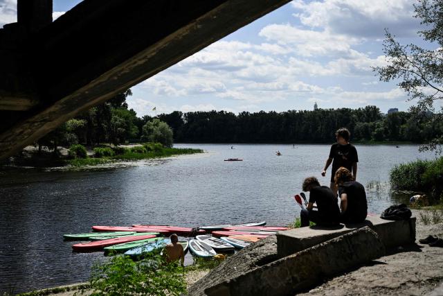 People relax by the Dnipro River during a hot summer’s day in Kyiv on June 27, 2026, amid the Russian invasion of Ukraine. Tens of millions face a weekend on June 27-28, 2026 of extreme temperatures in Europe as a deadly heatwave moves eastwards. (Photo by Genya SAVILOV / AFP)