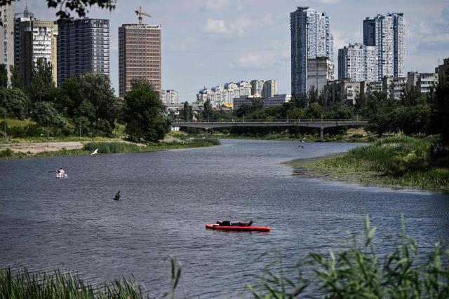A man relax as he lays on a paddle board along the Dnipro River during a hot summer’s day in Kyiv on June 27, 2026, amid the Russian invasion of Ukraine. Tens of millions face a weekend on June 27-28, 2026 of extreme temperatures in Europe as a deadly heatwave moves eastwards. (Photo by Genya SAVILOV / AFP)