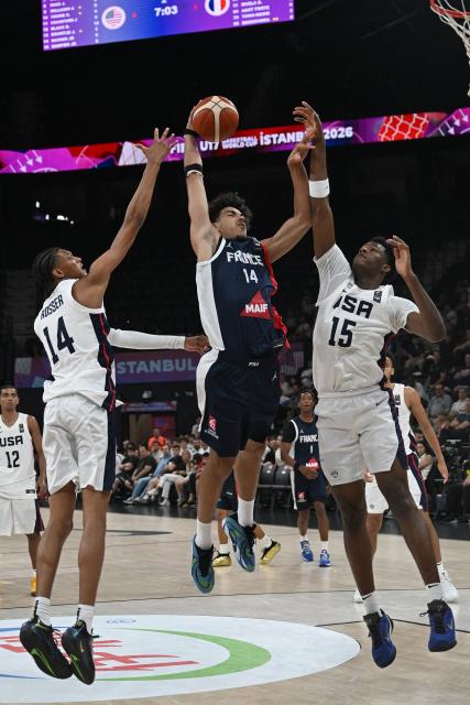 France's #14 Nathan Soliman (C) jumps to the net in front of USA's #14 Clarence Rosser Jr (L) and #15 Erick Dampier Jr during the U17 Basketball World Cup group match between France and USA in Istanbul on June 27, 2026. (Photo by Ozan KOSE / AFP)