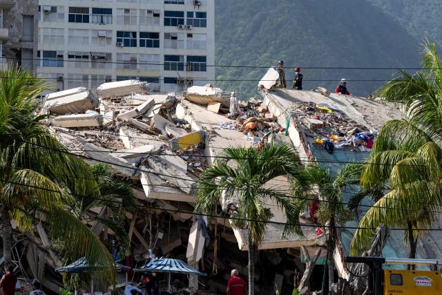 A collapsed building is seen from the base camp of the French Civil Security Training and Intervention Regiment (UIISC 7) at the Karting La Guaira complex in Caraballeda, La Guaira state, Venezuela, on June 27, 2026, as they assist with rescue operations following earthquakes. Nearly 1,000 people have been killed and more than 50,000 remain missing after two consecutive earthquakes in Venezuela, where growing anger has been reported over the lack of official aid to swiftly rescue survivors. (Photo by Miguel MEDINA / POOL / AFP)