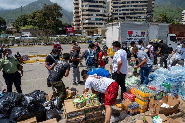 People receive donated food and drinks in Caraballeda, La Guaira state, Venezuela, on June 27, 2026, following earthquakes. Nearly 1,000 people have been killed and more than 50,000 remain missing after two consecutive earthquakes in Venezuela, where growing anger has been reported over the lack of official aid to swiftly rescue survivors. (Photo by Miguel MEDINA / POOL / AFP)