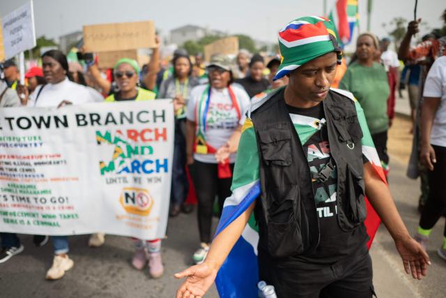 A group of about 80 people, some carrying banners and waving South African flags, take part in a march organised by March and March as they protest against undocumented migrants in Parklands, a suburb of Cape Town, on June 27, 2026. South Africans President Cyril Ramaphosa vowed on Thursday to crush any attempts to destabilise the nation during planned anti-immigrant marches next week, amid a wave of xenophobia. Citizen-led groups have set Tuesday 30 as a deadline for undocumented foreigners to leave and called for nationwide marches against illegal immigration, marking a crescendo in months of protests that have at times turned violent. (Photo by RODGER BOSCH / AFP)