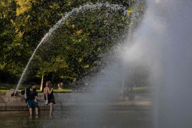 Residents of Warsaw cool off near a fountain in the city centre during the heatwave that has reached Poland on June 27, 2026. (Photo by Wojtek RADWANSKI / AFP)