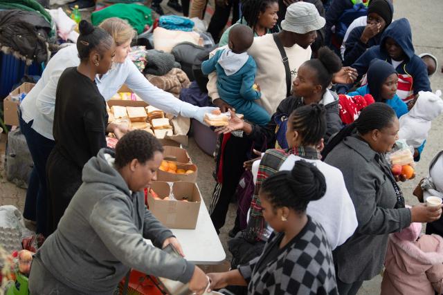 Volunteers distribute food to hundreds of Zimbabwean migrants gathered with their belongings outside the Zimbabwean Consulate in Cape Town, on June 27, 2026, as they try to get repatriated to Zimbabwe. South Africans President Cyril Ramaphosa vowed on Thursday to crush any attempts to destabilise the nation during planned anti-immigrant marches next week, amid a wave of xenophobia. Citizen-led groups have set Tuesday 30 as a deadline for undocumented foreigners to leave and called for nationwide marches against illegal immigration, marking a crescendo in months of protests that have at times turned violent. (Photo by RODGER BOSCH / AFP)
