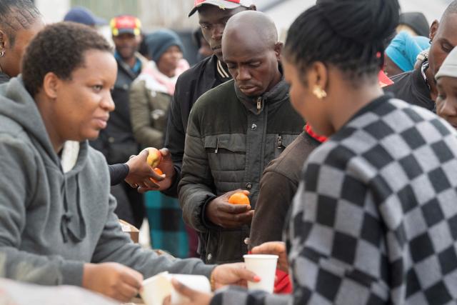 Volunteers distribute food to hundreds of Zimbabwean migrants gathered with their belongings outside the Zimbabwean Consulate in Cape Town, on June 27, 2026, as they try to get repatriated to Zimbabwe. South Africans President Cyril Ramaphosa vowed on Thursday to crush any attempts to destabilise the nation during planned anti-immigrant marches next week, amid a wave of xenophobia. Citizen-led groups have set Tuesday 30 as a deadline for undocumented foreigners to leave and called for nationwide marches against illegal immigration, marking a crescendo in months of protests that have at times turned violent. (Photo by RODGER BOSCH / AFP)