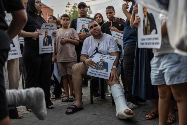 A teenager who was injured during the killing of Arab-Israeli teenager Ahmad Jabari sits with relatives and activists attending a memorial vigil in Jaffa on June 27, 2026. Jabari was shot on June 25 by an unidentified man on a scooter while he was working in a local supermarket, according to Israeli police. Another teenager was injured in the incident. (Photo by ilia YEFIMOVICH / AFP)
