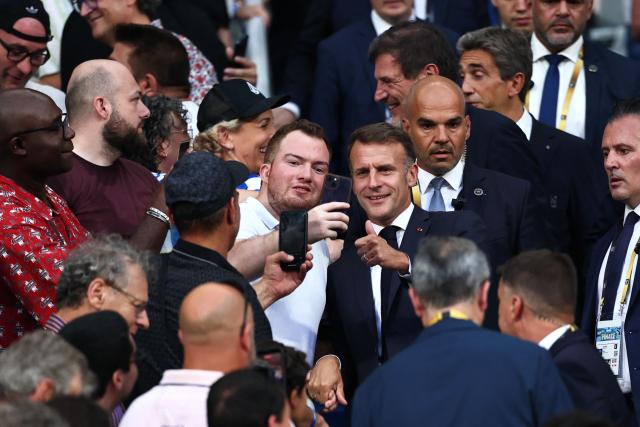 France's President Emmanuel Macron (R) poses for a selfie with a spectator prior to the French Top 14 rugby union final between Stade Toulousain (Toulouse) and Montpellier Hérault Rugby (MHR) at the Stade de France in Saint-Denis, on the outskirst of Paris, on June 27, 2026. (Photo by Anne-Christine POUJOULAT / AFP)