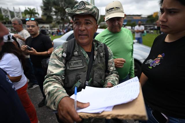 A member of the Bolivarian Militia registers the names of volunteers queueing to request permission to travel to La Guaira state to assist with rescue operations following earthquakes at the Poliedro in Caracas on June 27, 2026. Nearly 1,000 people have been killed and more than 50,000 remain missing after two consecutive earthquakes in Venezuela, where growing anger has been reported over the lack of official aid to swiftly rescue survivors. (Photo by Juan BARRETO / AFP)
