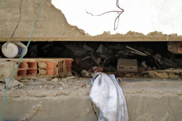 EDITORS NOTE: Graphic content / The body of a person is seen among the rubble of a collapsed building in Caraballeda, La Guaira state, Venezuela, on June 27, 2026, following earthquakes that struck the area. Nearly 1,000 people have been killed and more than 50,000 remain missing after two consecutive earthquakes in Venezuela, where growing anger has been reported over the lack of official aid to swiftly rescue survivors. (Photo by Mauricio VALENZUELA / AFP)