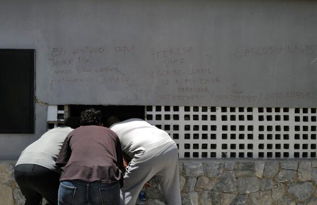 People look inside a damaged building in Caraballeda, La Guaira state, Venezuela, on June 27, 2026, following earthquakes. Nearly 1,000 people have been killed and more than 50,000 remain missing after two consecutive earthquakes in Venezuela, where growing anger has been reported over the lack of official aid to swiftly rescue survivors. (Photo by Mauricio VALENZUELA / AFP)