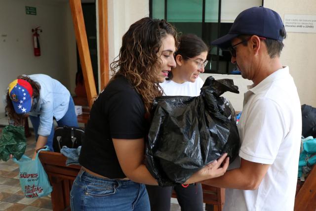 A man delivers a donation pack while Venezuelans living in Ecuador gather supplies for the victims of the twin earthquakes in their homeland, at an improvised collection centre in northern Quito, on June 27, 2026. The death toll in Venezuela's twin earthquake disaster reached 1,430, and millions more were feared to lack sanitation and other basic needs as the first US aid flights trickled into Caracas. (Photo by Galo Paguay / AFP)