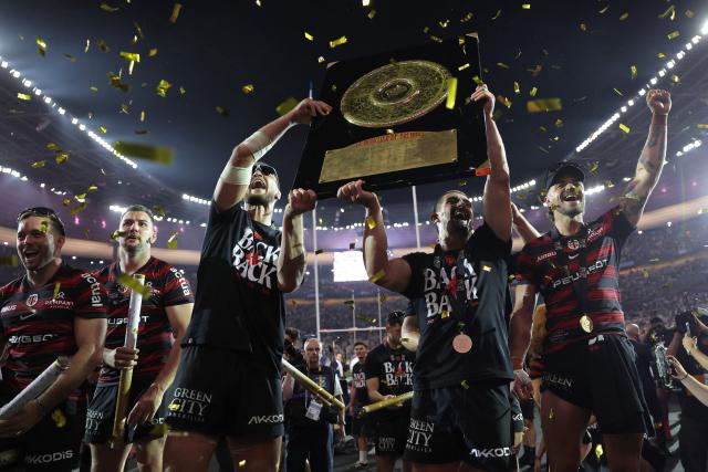 Toulouse's French fly-half Romain Ntamack (R) and Toulouse's French full-back Thomas Ramos (C) celebrate with the "Bouclier de Brennus" trophy after winning the French Top 14 rugby union final against Montpellier Hérault Rugby (MHR) at the Stade de France in Saint-Denis, on the outskirts of Paris, on June 27, 2026. (Photo by Kenzo TRIBOUILLARD / AFP)