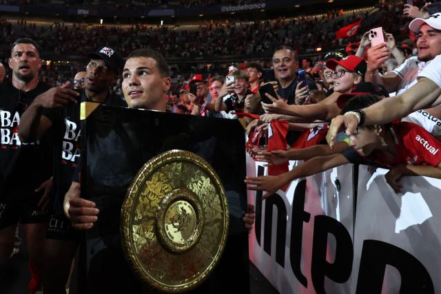 Toulouse's French scrum-half Antoine Dupont brings the "Bouclier de Brennus" trophy to supporters after winning the French Top 14 rugby union final against Montpellier Hérault Rugby (MHR) at the Stade de France in Saint-Denis, on the outskirts of Paris, on June 27, 2026. (Photo by Anne-Christine POUJOULAT / AFP)