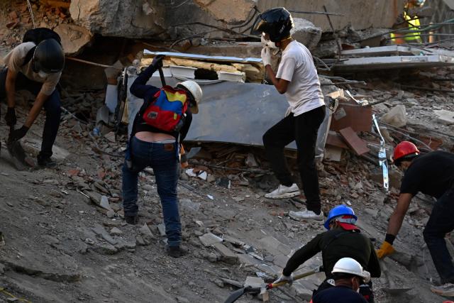 Volunteers work searching for possible victims at a collapsed building following twin earthquakes, in San Bernardino neighbourhood, in Caracas on June 27, 2026. The death toll in Venezuela's twin earthquake disaster reached 1,430 and millions more were feared to lack sanitation and other basic needs as the first US aid flights trickled into Caracas. (Photo by Juan BARRETO / AFP)