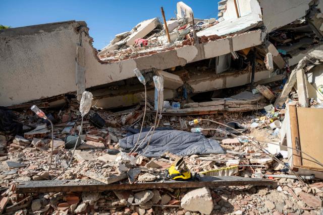 This photograph shows a covered dead body amid rubble of a collapsed building in Caraballeda, La Guaira state, Venezuela, on June 27, 2026, following earthquakes. Nearly 1,000 people have been killed and more than 50,000 remain missing after two consecutive earthquakes in Venezuela, where growing anger has been reported over the lack of official aid to swiftly rescue survivors. (Photo by Miguel MEDINA / POOL / AFP)