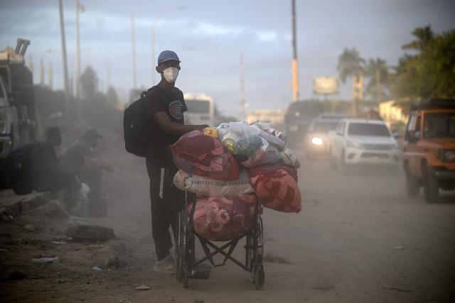 A man carrying supplies in a wheelchair walks amid dust following the twin earthquakes, in Los Corales, La Guaira state, some 40 km northeast of Caracas, on June 27, 2026. Three days after powerful tremors of magnitude 7.2 and 7.5 killed 1,430 people and left more than 50,000 missing, fury with perceived governmental inaction is mounting -- as is the feeling of helplessness. (Photo by Federico PARRA / AFP)