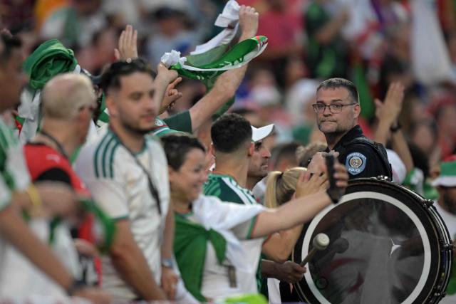 A Kansas City Police officer looks on next to an Algeria fan beating a drum ahead of the 2026 World Cup Group J football match between Algeria and Austria at the Kansas City Stadium in Kansas City on June 27, 2026.  (Photo by JUAN MABROMATA / AFP)