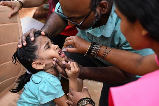 A health worker administers oral polio vaccine to a child during the nationwide Pulse Polio Immunisation Program at a school in Bengaluru on June 28, 2026. (Photo by Idrees MOHAMMED / AFP)