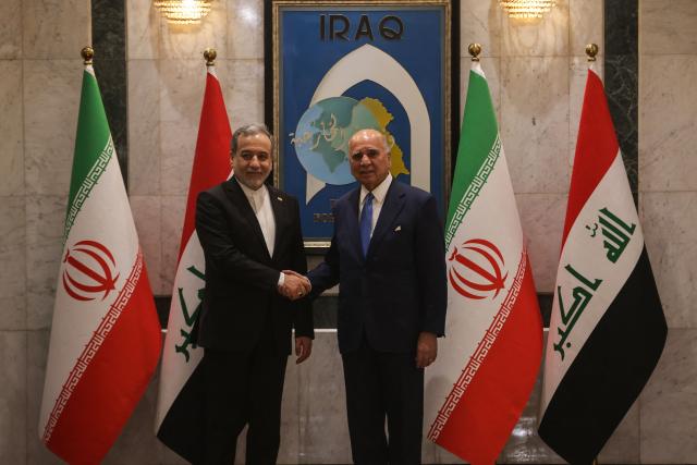 Iraqi Foreign Minister Fuad Hussein (R) shakes hands with his Iranian counterpart, Foreign Minister Abbas Araqchi during an official visit to Baghdad on July 28, 2026. Iran said on June 28, it was determined to defend its sovereignty after the latest US strikes on the country, as a fragile truce in the Middle East war hung in the balance. (Photo by AHMAD AL-RUBAYE / AFP)