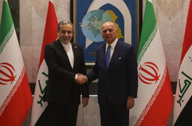 Iraqi Foreign Minister Fuad Hussein (R) shakes hands with his Iranian counterpart, Foreign Minister Abbas Araqchi during an official visit to Baghdad on July 28, 2026. Iran said on June 28, it was determined to defend its sovereignty after the latest US strikes on the country, as a fragile truce in the Middle East war hung in the balance. (Photo by AHMAD AL-RUBAYE / AFP)