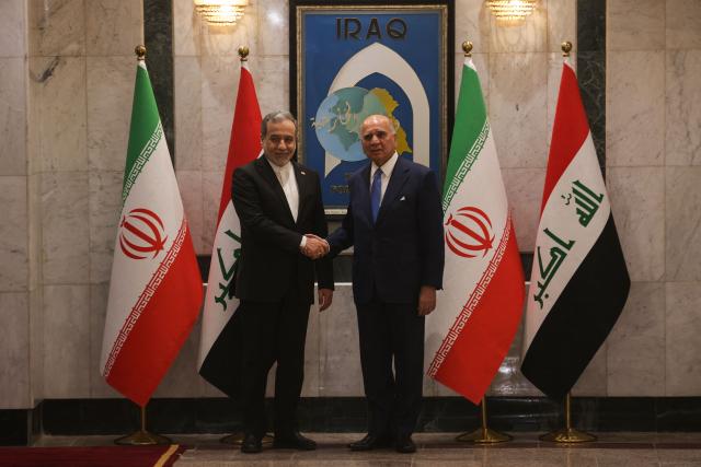 Iraqi Foreign Minister Fuad Hussein (R) shakes hands with his Iranian counterpart, Foreign Minister Abbas Araqchi during an official visit to Baghdad on July 28, 2026. Iran said on June 28, it was determined to defend its sovereignty after the latest US strikes on the country, as a fragile truce in the Middle East war hung in the balance. (Photo by AHMAD AL-RUBAYE / AFP)