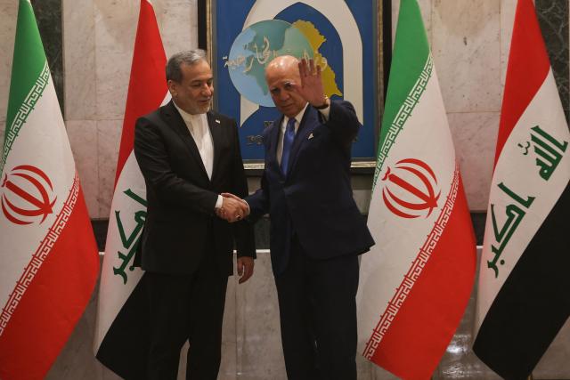 Iraqi Foreign Minister Fuad Hussein (R) shakes hands with his Iranian counterpart, Foreign Minister Abbas Araqchi during an official visit to Baghdad on July 28, 2026. Iran said on June 28, it was determined to defend its sovereignty after the latest US strikes on the country, as a fragile truce in the Middle East war hung in the balance. (Photo by AHMAD AL-RUBAYE / AFP)