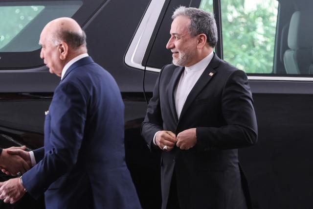 Iraqi Foreign Minister Fuad Hussein (L) greets a member of the Iranian delegation, as Iranian Foreign Minister Abbas Araqchi (R) looks on, upon his arrival in Baghdad on July 28, 2026. Iran said on June 28, it was determined to defend its sovereignty after the latest US strikes on the country, as a fragile truce in the Middle East war hung in the balance. (Photo by AHMAD AL-RUBAYE / AFP)