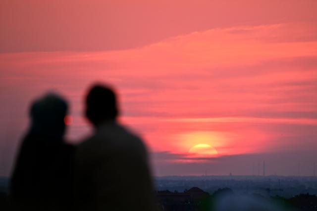 A couple watches the sun going up on early June 28, 2026, over the Drachenberg mountain in Berlin, as the German capital is expected to reach teperatures around 40 degrees Celsius during a heatwave in Europe. Tens of millions are braving a weekend of extreme temperatures in Europe as a deadly heatwave moves eastwards, with some countries announcing rising death tolls and health services warning of saturation. While some mild relief is expected Sunday in western Europe, German forecasters are warning that more temperature records could still be broken over the weekend as eastern countries issue a slew of red alerts for the coming days. (Photo by RALF HIRSCHBERGER / AFP)