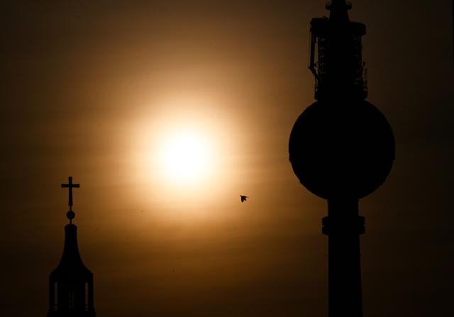 Berlin's landmark TV tower and a tower of the cathedral are silhouetted next to the rising sun on early June 28, 2026, in Berlin, as the German capital is expected to reach teperatures around 40 degrees Celsius during a heatwave in Europe. Tens of millions are braving a weekend of extreme temperatures in Europe as a deadly heatwave moves eastwards, with some countries announcing rising death tolls and health services warning of saturation. While some mild relief is expected Sunday in western Europe, German forecasters are warning that more temperature records could still be broken over the weekend as eastern countries issue a slew of red alerts for the coming days. (Photo by RALF HIRSCHBERGER / AFP)