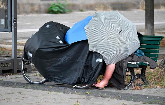 A homeless person on a public bench shelters under umbrellas on early June 28, 2026, in Berlin, as the German capital is expected to reach teperatures around 40 degrees Celsius during a heatwave in Europe. Tens of millions are braving a weekend of extreme temperatures in Europe as a deadly heatwave moves eastwards, with some countries announcing rising death tolls and health services warning of saturation. While some mild relief is expected Sunday in western Europe, German forecasters are warning that more temperature records could still be broken over the weekend as eastern countries issue a slew of red alerts for the coming days. (Photo by RALF HIRSCHBERGER / AFP)