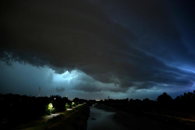 Lightnings flashes in the clouds as a severe storm looms over a canal in Sint-Pieters-Leeuw, near Brussels, on June 28, 2026. (Photo by Nicolas TUCAT / AFP)